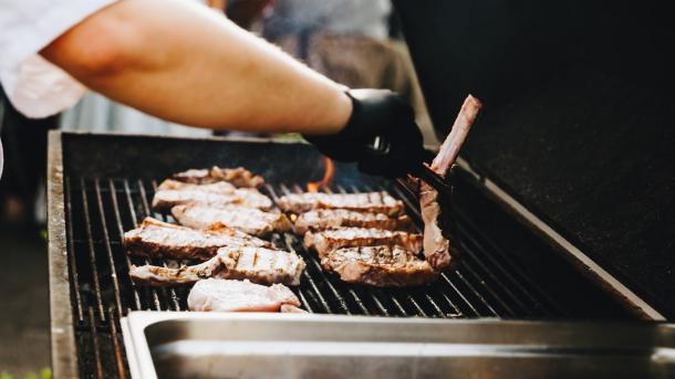 Mand vender bøffer på en grill