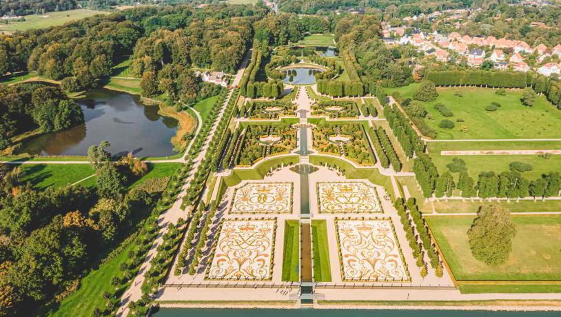 Barokhaven ved Frederiksborg Slot set fra luften med de symmetriske stier og opalsøen.
