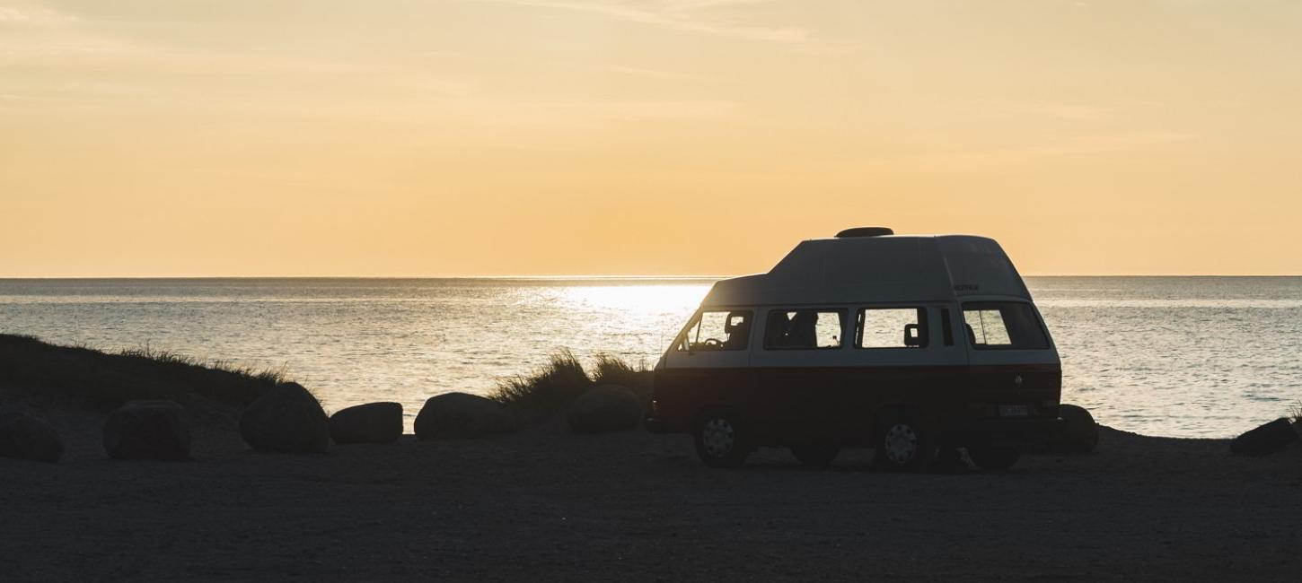 En van holder i strandkanten og aftensolen skinner i havet i Nordsjælland