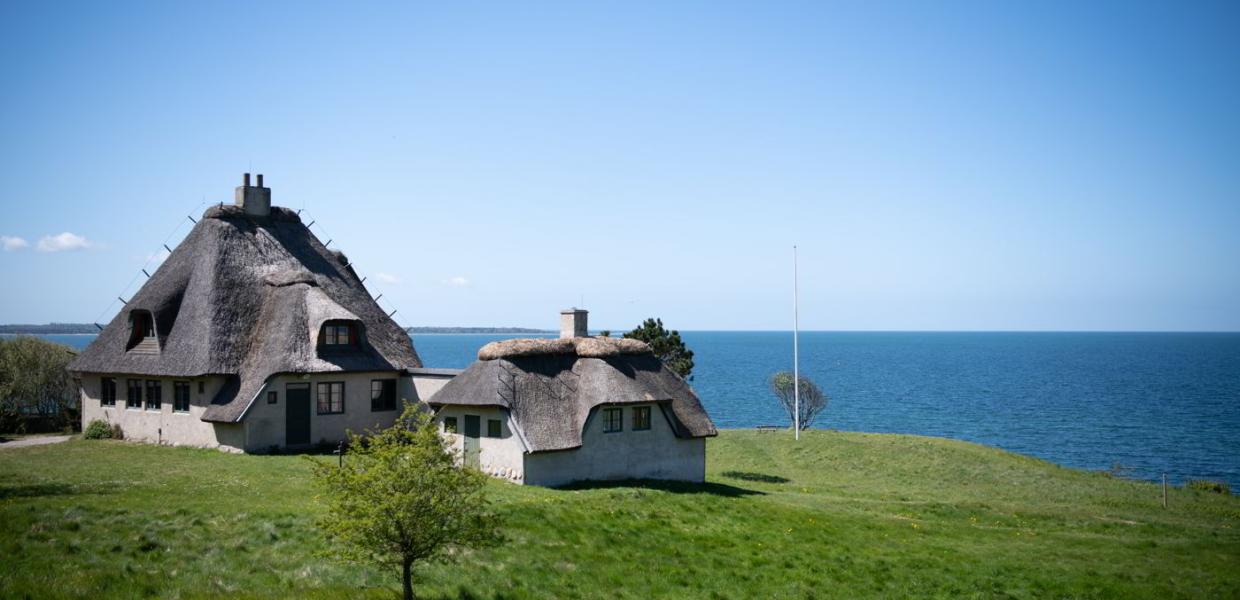 Knud Rasmussens Hus i Hundested ligger klar til at byde dig velkommen oppe på skrænten med havet bagved.