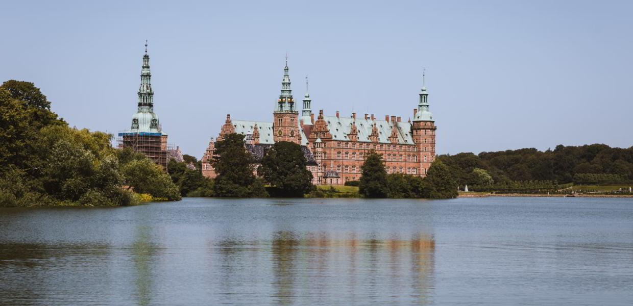 Frederiksborg Slot med slottsøen foran set fra Torvet i Hillerød på en sommerdag..
