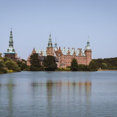 Frederiksborg Slot med slottsøen foran set fra Torvet i Hillerød på en sommerdag..