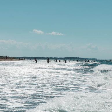 Børn og voksne kaster sig i bølgerne på Tisvildeleje Strand i Nordsjælland