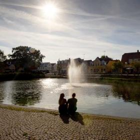 Et par sidder og kigger ud over Helsinge gadekær i aftensolen